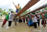 Sejumlah warga bergotong rotong membangun jembatan darurat di Desa Tulabolo, Kabupaten Bone Bolango, Gorontalo. Jembatan yang terbuat dari kayu kelapa tersebut dibangun agar akses kecamatan Suwawa dan Kecamatan Pinogu kembali terhubung pascabanjir yang menghanyutkan jembatan utama pada Jumat (3/7) lalu. (ANTARA FOTO/Adiwinata Solihin)