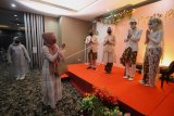 Tamu undangan memberikan ucapan selamat kepada pasangan pengantin Kumala dan Putri beserta keluarganya dengan menjaga jarak fisik saat simulasi resepsi pernikahan di masa normal baru di Hotel Royal Singosari Cendana, Surabaya, Jawa Timur, Senin (6/7/2020). Kegiatan simulasi resepsi pernikahan tersebut bertujuan untuk mengedukasi masyarakat tentang pentingnya penerapan protokol kesehatan dalam acara pernikahan guna mencegah penyebaran dan penularan COVID-19 di masa normal baru. ANTARA FOTO/Moch Asim/wsj.
