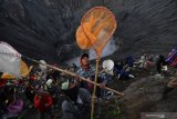 Warga berebut sesaji yang dilempar oleh masyarakat Suku Tengger ke kawah Gunung Bromo dalam rangka perayaan Yadnya Kasada, Probolinggo, Jawa Timur, Selasa (7/7/2020). Perayaan Yadnya Kasada merupakan bentuk ungkapan syukur dan penghormatan kepada leluhur masyarakat Suku Tengger dengan cara melarung sesaji berupa hasil bumi dan ternak ke kawah Gunung Bromo. Antara Jatim/Zabur Karuru