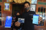 Territory Sales Manager XL Axiata area Bangkalan-Sampang Prasetyo Anugroho menunjukkan produk unggulan XL dan aplikasi MyXL (kanan) bersama pemenang Xtravaganza dan FantAXIS 12 Zahratul Gamelia (kiri) saat penyerahan hadiah di Desa Kamondung, Sampang, Jawa Timur, Jumat (10/7/2020). Zahratul Gamelia menjadi pemenang hadiah Rp100 juta Program Xtravaganza dan FantAXIS yang merupakan program apresiasi atas loyalitas pelanggan XL Axiata, baik yang menggunakan nomor prabayar XL dan AXIS, maupun pascabayar XL Prioritas. Antara Jatim/Saiful Bahri/zk