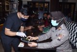 Petugas resto memberi penjelasan kepada seorang perwira polisi dalam memilih menu dan melakukan transaksi menggunakan aplikasi di telepon genggam saat peluncuran Resto Tangguh Semeru di sebuah resto bakso di Kota Madiun, Jawa Timur, Sabtu (11/7/2020) malam. Pemkot bersama Polres Madiun Kota meluncurkan Resto Tangguh Semeru yang telah menerapkan secara ketat protokol kesehatan pencegahan penyebaran COVID-19 dan diharapkan resto bakso yang telah diresmikan tersebut bisa menjadi percontohan bagi resto yang lain. Antara Jatim/Siswowidodo/zk