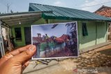 Pemilik rumah tidak layak huni (RTLH) menunjukan foto pembangunan rumah yang dibangun oleh Kesatuan TNI Yon Armed 10 Bradjamusti Kostrad di Sukaraja, Kabupaten Bogor, Jawa Barat, Sabtu (11/7/2020). Bantuan bedah rumah tidak layak huni tersebut merupakan bakti sosial TNI membangun desa, serta sebagai rangkaian HUT Yon Armed 10 Bradjamusti Kostrad. (fOTO: ANTARA FOTO/Yulius Satria Wijaya).