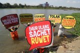 Aktivis lingkungan hidup dari Ecological Observation and Wetlands Conservation (Ecoton) membentangkan poster saat aksi tolak pencemaran sungai Brantas di Kota Kediri, Jawa Timur, Minggu (12/7/2020). Tim peneliti Ecoton menemukan sejumlah polutan berbahaya di sungai terpanjang ke dua di pulau Jawa tersebut yakni di antaranya kandungan mikroplastik yang dapat merusak ekosistem dan berbahaya bagi kesehatan manusia. Antara Jatim/Prasetia Fauzani/zk