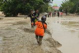 Petugas SAR dan warga melintasi lumpur akibat banjir bandang di Desa Radda, Kabupaten Luwu Utara, Sulawesi Selatan, Selasa (14/7/2020). Petugas BPBD Sulawesi Selatan masih menginventarisasi kerugian akibat banjir bandang pada Senin, 13 Juli 2020 yang mengakibatkan puluhan rumah terbawa arus, dua orang meninggal dan tujuh orang hilang. ANTARA FOTO/Indra/wpa/foc.