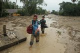 Dua warga melintasi lumpur akibat banjir bandang di Desa Radda, Kabupaten Luwu Utara, Sulawesi Selatan, Selasa (14/7/2020). Petugas BPBD Sulawesi Selatan masih menginventarisasi kerugian akibat banjir bandang pada Senin, 13 Juli 2020 yang mengakibatkan puluhan rumah terbawa arus, dua orang meninggal dan tujuh orang hilang. ANTARA FOTO/Indra/wpa/foc.