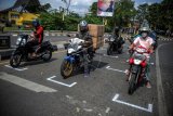 Pengendara sepeda dan motor berhenti di garis yang dibuat secara berjarak di perempatan Pemda Soreang, Kabupaten Bandung, Jawa Barat, Kamis (16/7/2020). Pembuatan jarak bagi pengendara sepeda motor tersebut ditujukan untuk mengantisipasi penyebaran COVID-19 di kawasan umum. ANTARA FOTO/Raisan Al Farisi/nz