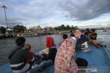 Warga menikmati pemandangan saat wisata susur Sungai Martapura di Banjarmasin, Kalimantan Selatan, Jumat (17/7/2020). Wisata susur Sungai Martapura tersebut menawarkan suasana alam serta aktivitas warga di bantaran sungai saat akhir pekan banyak didominasi wiasatawan domestik maupun warga lokal untuk bersantai bersama keluarga serta kerabat. Foto Antaranews Kalsel/Bayu Pratama S.