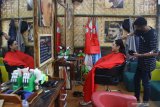 Narapidana memberikan layanan perawatan rambut pada seorang pengunjung di unit usaha kafe dan rumah pangkas rambut (barbershop) yang diberi nama Jagongan Jail di jalan Asahan, Malang, Jawa Timur, Jumat (17/7/2020). Unit usaha kafe dan rumah pangkas rambut tersebut didirikan Lembaga Pemasyarakatan (Lapas) Kelas 1 Lowokwaru-Malang yang bekerjasama dengan Koperasi Pegawai Lapas untuk memberikan ketrampilan wirausaha bagi narapidana yang lolos seleksi agar produktif serta siap terjun kembali ke masyarakat setelah bebas nanti. Antara Jatim/Ari Bowo Sucipto/zk.