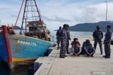 Komandan KRI Yos Sudarso-353 Letkol Laut (P) Maman Nurachman (kanan) berserta prajurit TNI AL awak KRI Yos Sudarso-353 mengiring para tahanan awak Kapal Ikan Asing (KIA) Vietnam yang berhasil diamankan di Pelabuhan Fasilitas labuh (Faslabuh) TNI AL di Selat Lampa Natuna, Kepulauan Riau, Sabtu (18/7/2020). KRI Yos Sudarso-353 berhasil menangkap kedua KIA tersebut di perairan Pulau Sekatung dan mengamankan 10 orang WNA beserta barang bukti ikan hasil tangkapannya. Antara Jatim/Ardi/ZK