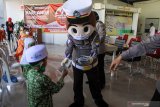Badut Polisi memberikan masker kepada anak anak dalam rangka peringatan Hari Anak Nasional di Balai Desa Pepelegi, Waru, Sidoarjo, Jawa Timur, Rabu (22/7/2020). Peringatan Hari Anak Nasional yang jatuh setiap tanggal 23 Juli mengambil tema 