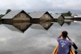 Warga menggunakan rakit melintasi rumah yang terendam banjir di Desa Laloika, Kecamatan Pondidaha, Kabupaten Konawe, Sulawesi Tenggara, Rabu (22/7/2020). Banjir akibat luapan Sungai Konaweha dan Sungai Lahambuti yang merendam di tiga Desa Laloika, Wonuamonapa dan Desa Lalonggotomi mencapai ketinggian empat meter. ANTARA FOTO/Jojon/nym.