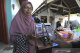 Petugas Bank Indonesia (BI) Cirebon menunjukan transaksi melalui aplikasi elektronik di Desa Kenanga, Indramayu, Jawa Barat, Jumat (24/7/2020). Bank Indonesia (BI) Cirebon bekerjasama dengan Keluarga Migran Indonesia (KAMI) Jabar memberikan edukasi dan pembuatan Quick Response Indonesia Standard (QRIS) untuk pelaku UMKM untuk mendorong efisiensi transaksi, mempercepat inklusi keuangan, memajukan UMKM dan mendorong pertumbuhan ekonomi. ANTARA JABAR/Dedhez Anggara/agr