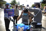 Petugas mengenakan masker kepada seorang pengguna kendaraan saat Operasi Patuh Lodaya di Bunderan Binokasih, Kabupaten Sumedang, Jawa Barat, Sabtu (25/7/2020). Polres Sumedang membagikan 7.500 masker bantuan dari Pemprov Jabar  kepada pengendara dan penumpang kendaraan umum pada operasi Patuh Lodaya yang digelar selama dua minggu guna mencegah penyebaran COVID-19. ANTARA JABAR/Raisan Al Farisi/agr