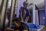 Terapis tuna netra memijat pelanggan dengan menggunakan pelindung wajah di Rumah Bugar Wyata Guna, Bandung, Jawa Barat, Selasa (28/7/2020). Rumah bugar atau panti pijat tuna netra tersebut mulai kembali beroperasi di masa adaptasi kebiasaan baru dengan menerapkan protokol kesehatan yang ketat sekaligus pemberdayaan dan pemulihan ekonomi bagi penyandang tuna netra yang bekerja di tempat tersebut. ANTARA JABAR/Novrian Arbi/agr