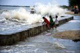 Pengunjung mandi di Pantai Wisata Jumiang ketika sedang  ombak besar, Pamekasan, Jawa Timur, Minggu (2/8/2020). Kendati cuaca laut di awal Bulan Agustus ini, sedang tidak bersahabat, namun justru semakin menambah daya tarik pengunjung untuk menikmati sensasi mandi diantara deburan ombak besar. Antara Jatim/Saiful Bahri/zk