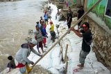 Seorang pekerja mengangkat karung berisi pasir untuk pembangunan tanggul darurat di tepi Sungai Bone, Kelurahan Bugis, Kota Gorontalo, Gorontalo, Kamis (6/8/2020). Pemerintah Provinsi Gorontalo mulai membangun tanggul sungai darurat setelah tanggul dan bronjong di wilayah itu hancur diterjang banjir sebanyak sembilan kali. (ANTARA FOTO/Adiwinata Solihin)