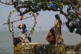 Pengunjung memotret rekannya di salah satu tempat untuk berfoto saat berwisata di Pantai Gua Petapa, Sukolilo, Bangkalan, Jawa Timur, Sabtu (8/8/2020). Obyek wisata yang menyuguhkan pemandangan pantai dan gua di Kabupaten Bangkalan tersebut mulai ramai dikunjungi wisatawan saat akhir pekan di tengah pandemi COVID-19. Antara Jatim/Moch Asim/zk.