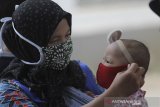 Seorang ibu memasang masker untuk anaknya yang akan diberi imunisasi di Posyandu Kunir, desa Sukaurip, Balongan, Indramayu, Jawa Barat, Senin (10/8/2020). Pemerintah mulai mengaktifkan posyandu desa yang sempat terhenti sejak pandemi COVID-19 dengan memperketat protokol kesehatan dan menyesuaikan kondisi adaptasi kebiasaan baru. ANTARA JABAR/Dedhez Anggara/agr