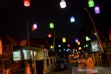 Warga berswafoto dengan latar belakang lampu lampion di Lembur Situ, Kabupaten Ciamis, Jawa Barat, Selasa (11/8/2020). Pernak-pernik seperti lampion, bendera, dan umbul-umbul yang dibuat dari hasil kreasi masyarakat secara gotong royong tersebut dipasang disepanjang jalan dalam rangka memeriahkan perayaan HUT ke-75 Kemerdekaan Republik Indonesia. ANTARA JABAR/Adeng Bustomi/ agr