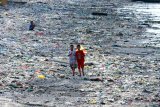 Anak-anak bermain layang-layang diantara tumpukan sampah di Pelabuhan Muncar, Banyuwangi, Jawa Timur, Selasa (11/8/2020). Menurut warga sekitar, sampah yang menumpuk disepanjang pantai akibat banjir besar pada tahun 2014 itu, juga diperparah oleh kebiasaan warga yang membuang sampah ditempat itu. Antara Jatim/Budi Candra Setya/zk.