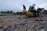 Nelayan memperbaiki kapal diantara tumpukan sampah di Pelabuhan Muncar, Banyuwangi, Jawa Timur, Selasa (11/8/2020). Menurut warga sekitar, sampah yang menumpuk disepanjang pantai akibat banjir besar pada tahun 2014 itu, juga diperparah oleh kebiasaan warga yang membuang sampah ditempat itu. Antara Jatim/Budi Candra Setya/zk.