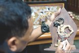 Perajin menyelesaikan pembuatan wayang hias berbahan limbah kayu jati hasil kreasinya di Tulungagung, Jawa Timur, Kamis (13/8/2020). Wayang kayu untuk hiasan dinding seukuran telapak tangan orang dewasa itu dijual Rp250 ribu per buah hingga Rp2 juta per set isi empat buah wayang kayu plus piguranya. Antara Jatim/Destyan Sujarwoko/zk