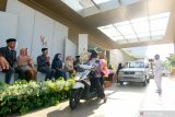 Pasangan Vicky dan Hermisa menyapa tamu pada resepsi pernikahannya yang digelar berkonsep lantatur (drive thru) di Banyuwangi, Jawa Timur, Kamis (13/8/2020). Konsep resepsi pernikahan drive thru, kini menjadi solusi bagi para pengantin yang hendak menggelar resepsi atau hajatan di tengah pandemi COVID-19. Antara Jatim/Budi Candra Setya/zk.