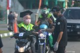 Petugas menyemprot tangan wisudawan dengan cairan disinfektan saat mengikuti prosesi wisuda secara Drive Thru di Institut Agama Islam Negeri (IAIN) Jember, Jawa Timur, Sabtu (15/8/2020). Wisuda Drive Thru tersebut digelar IAIN Jember dalam situasi adaptasi kebiasaan baru ditengah pandemi COVID-19. Antara Jatim/Seno/zk