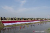 Komunitas Pasukan Susur Sungai dan Ekosistem Rancaekek (Passer) membentangkan kain Merah Putih di bantaran sungai Cikijing, Rancaekek, Kabupaten Bandung, Jawa Barat, Minggu (16/8/2020). Pemasangan kain Merah Putih berukuran 75X3 meter di bantaran sungai tersebut untuk menyambut perayaan HUT ke-75 kemerdekaan Republik Indonesia. ANTARA JABAR/M Agung Rajasa/agr