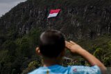 Seorang anak melakukan sikap hormat ke arah bendera merah putih yang dikibarkan di Tebing Gunung Batu, Lembang, Kabupaten Bandung Barat, Senin (17/8/2020). Komunitas Pecinta alam bersama karang taruna lembang mengibarkan bendera merah putih berukuran 8x12 meter di tebing kawasan Sesar Lembang dengan ketinggian 1228 meter dari pemukaan laut sebgai peringatan HUT Ke-75 Kemerdekaan Republik Indonesia. ANTARA JABAR/Novrian Arbi/agr