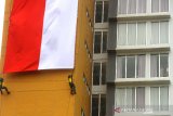 Warga menyaksikan pengibaran bendera merah putih dari balik jendela di Aston Banua Hotel dan Convention Center, Kabupaten Banjar, Kalimantan Selatan, Senin (17/8/2020). Manajemen Hotel tersebut berkerjasama dengan TNI dan POLRI mengibarkan bendera merah putih sepanjang kurang lebih 100 meter pada gedung tertinggi yang berada di Kalimantan Selatan untuk memperingati Hari Kemerdekaan ke-75 Republik Indonesia. Foto Antaranews Kalsel/Bayu Pratama S.