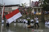 Warga mengibarkan bendera merah putih saat mengikuti upacara bendera di Daerah Aliran Sungai (DAS) Cileueur, Lingkungan Janggala, Kabupaten Ciamis, Jawa Barat, Senin (17/8/2020). Upacara di sungai dengan menerapkan protokol kesehatan COVID-19 itu digelar untuk memperingati HUT Ke-75 RI sekaligus menumbuhkan kesadaran warga untuk peduli terhadap lingkungan agar terbebas dari sampah. ANTARA JABAR/Adeng Bustomi/agr