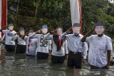 Warga memakai topeng para Presiden RI memberi hormat kepada bendera merah putih saat mengikuti upacara bendera di Daerah Aliran Sungai (DAS) Cileueur, Lingkungan Janggala, Kabupaten Ciamis, Jawa Barat, Senin (17/8/2020). Upacara di sungai dengan menerapkan protokol kesehatan COVID-19 itu digelar untuk memperingati HUT Ke-75 RI sekaligus menumbuhkan kesadaran warga untuk peduli terhadap lingkungan agar terbebas dari sampah. ANTARA JABAR/Adeng Bustomi/agr