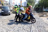 Anggota Satlantas Polresta Sidoarjo membantu mendorong pengendara sepeda motor yang melintas di atas jalur rel yang diperbaiki di perlintasan kereta api kawasan Lingkar Timur, Buduran, Sidoarjo, Jawa Timur, Senin (31/8/2020). Kegiatan tersebut untuk mengantisipasi terjadinya kecelakaan saat melintas di lokasi tersebut. Antara Jatim/Umarul Faruq/zk