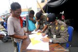 Petugas Satpol PP mendata warga yang melanggar protokol kesehatan di kawasan Pasar Lima Banjarmasin, Kalimantan Selatan, Selasa (1/9/2020). Sebagai upaya pencegahan dan pengendalian COVID-19, Pemerintah Kota Banjarmasin menerapkan sanksi denda sebesar Rp100 ribu serta sanksi sosial bagi warga yang tidak menggunakan masker saat beraktivitas diluar rumah. Foto Antaranews Kalsel/Bayu Pratama S.