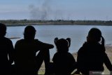 Sejumlah orang berada di tepi Waduk Notopuro dengan latar belakang kawasan Hutan Saradan yang terbakar di Kabupaten Madiun, Jawa Timur, Selasa (1/9/2020). Menurut warga kawasan hutan tersebut beberapa kali terbakar selama musim kemarau ini dan belum diketahui penyebabnya. Antara Jatim/Siswowidodo/zk