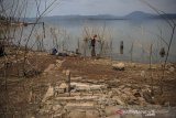 Warga mencari ikan di antara kompleks pemakaman yang muncul kembali ke permukaan di pinggiran Waduk Jatigede, Desa Cipaku, Darmaraja, Kabupaten Sumedang, Jawa Barat, Selasa (8/9/2020). Masyarakat setempat menyatakan, musim kemarau yang telah terjadi selama dua bulan di Kabupaten Sumedang membuat debit air Waduk Jatigede menyusut hingga sekitar 5 meter dan membuat bekas permukiman serta kompleks pemakaman muncul ke permukaan. ANTARA JABAR/Raisan Al Farisi/agr