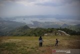 Wisatawan menikmati pemandangan Waduk Jatigede di wisata alam Puncak Batu Dua, Cisitu, Kabupaten Sumedang, Jawa Barat, Selasa (8/9/2020). Wisata Puncak Batu Dua menjadi potensi ekonomi melalui sektor pariwisata di Kabupaten Sumedang yang menawarkan panorama Waduk Jatigede, Gunung Tampomas, dan Lansekap Kota Sumedang. ANTARA JABAR/Raisan Al Farisi/agr