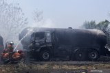 Petugas Dinas Pemadam Kebakaran Kota Surabaya melakukan pembasahan truk tangki yang terbakar di kawasan Dumar Industri, Surabaya, Jawa Timur, Sabtu (12/9/2020). Sekitar 18 kendaraan pemadam kebakaran dikerahkan untuk memadamkan kebakaran diduga berawal dari kebakaran alang-alang yang merembet serta membakar lima truk tangki tersebut. Antara Foto/Didik/Zk