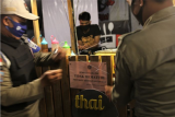 Petugas keamanan dan Dinas Kesehatan memasang pengumuman sanksi Tidak Mematuhi Protokol Kesehatan COVID-19 kepada seorang pedagang kuliner, di kompleks kuliner di Kendari, Sulawesi Tenggara, Senin (14/9/2020).Belasan pedagang kuliner menolak menerima sanksi berupa menempelan kertas bertulisan 