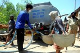 Relawan memasukkan air ke dalam timba saat pendistribusian air bersih di Desa Pamoroh, Pamekasan, Jawa Timur, Kamis (17/9/2020). Distribusi air bersih yang disalurkan oleh Forum Relawan Penanggulangan Bencana (FRPB) yang dilakukan sejak beberapa waktu lalu, guna membantu warga yang terdampak kekeringan akibat musim kemarau. Antara Jatim/Saiful Bahri/zk