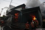 Petugas Dinas Pemadam Kebakaran Kota Surabaya memadamkan gudang yang terbakar di Jalan Niaga Tambang, Surabaya, Jawa Timur, Kamis (17/9/2020). Sekitar 21 kendaraan pemadam kebakaran dikerahkan untuk memadamkan api yang meludeskan gudang penyimpanan mesin jahit tersebut. Antara Jatim/Didik/Zk