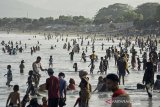 Ratusan wisatawan mengunjungi kawasan wisata Pantai Santolo, Pameungpeuk, Kabupaten Garut, Jawa Barat, Minggu (20/9/2020). Pantai Santolo menjadi salah satu destinasi wisata populer di Garut bagian selatan yang memiliki bentang pantai yang cukup panjang dan ramai dikunjungi wisatawan domestik maupun mancanegara. ANTARA JABAR/Candra Yanuarsyah/agr