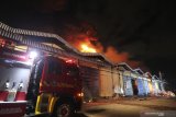 Petugas Dinas Pemadam Kebakaran Kota Surabaya memadamkan gudang yang terbakar di komplek pergudangan Margomulyo Jaya, Surabaya, Jawa Timur, Selasa (22/9/2020) malam. Sekitar 34 kendaraan pemadam kebakaran dikerahkan untuk memadamkan api yang meludeskan tiga gudang beserta isinya di komplek tersebut. Antara Jatim/Didik/Zk