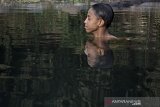 Seorang anak berendam di kawasan wisata Situ Cihariang, Karangtengah, Kabupaten Garut, Jawa Barat, Jumat (25/9/2020). Presiden Joko Widodo meminta kepada setiap desa untuk mengembangkan potensi lokal seperti pertanian, wisata dan industri di desa seluruh Indonesia dengan dukungan fasilitas yang diperlukan guna memperkuat perekonomian desa. ANTARA JABAR/Candra Yanuarsyah/agr