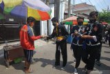 Pesilat membagikan masker kepada pedagang di Pasar Kutisari, Surabaya, Jawa Timur, Jumat (25/9/2020). Polsek Tenggilis bersama sejumlah pesilat dari berbagai perguruan silat di Surabaya membagikan ratusan masker kepada pedagang pasar dan warga yang bertujuan untuk memberikan pemahaman dan meningkatkan disiplin masyarakat menerapkan protokol kesehatan. Antara Jatim/Didik/Zk