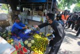 Pesilat membagikan masker kepada pedagang di Pasar Kutisari, Surabaya, Jawa Timur, Jumat (25/9/2020). Polsek Tenggilis bersama sejumlah pesilat dari berbagai perguruan silat di Surabaya membagikan ratusan masker kepada pedagang pasar dan warga yang bertujuan untuk memberikan pemahaman dan meningkatkan disiplin masyarakat menerapkan protokol kesehatan. Antara Jatim/Didik/Zk