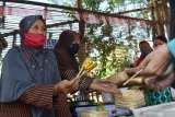 Penjual melayani pembeli di Pasar Pundensari di Desa Gunungsari Kabupaten Madiun, Jawa Timur, Minggu (27/9/2020). Pasar tradisional di desa wisata yang menyediakan berbagai makanan, jajanan dan minuman tradisional tersebut memiliki keunikan yaitu para penjualnya mengenakan pakaian tradisional dan seluruh pembayaran transaksi menggunakan bilah bambu yang sebelumnya didapat pengunjung dari panitia dengan mengganti sejumlah uang. Antara Jatim/Siswowidodo/zk.