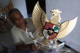 Ikhwan Erwantoro (68), membungkus kerajinan lambang negara Garuda Pancasila di Desa Diwek, Kabupaten Jombang, Jawa Timur, Rabu (30/09/2020). Kerajinan garuda berbahan kayu yang sempat terhenti sejak Maret 2020 akibat pandemi COVID-19 itu kini mulai bangkit kembali dengan menerima berbagai pesanan meski tidak sebanyak sebelumnya, dan dijual mulai harga Rp 90 ribu-Rp 2,5 juta tergantung ukuran. Antara Jatim/Syaiful Arif/zk.