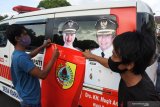 Pekerja menutup foto calon Bupati Jember petahana Faida di mobil Ambulans Desa di depan Kantor Pemkab Jember, Jawa Timur, Sabtu (3/10/2020). Bawaslu meminta foto diri petahana di fasilitas Pemkab Jember ditertibkan di masa kampanye Pilkada Jember 2020, termasuk yang menempel di 248 ambulans desa dan kelurahan. Antara Jatim/Seno/zk.